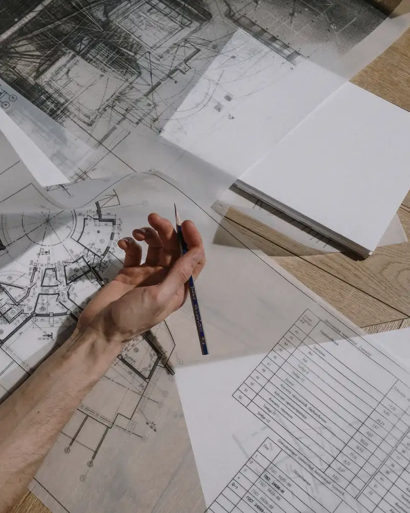 A designer sketching over plan drawings