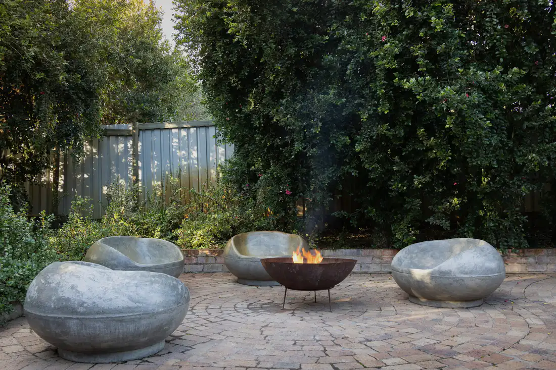 Stone chairs around a steel fire bowl on a paver patio
