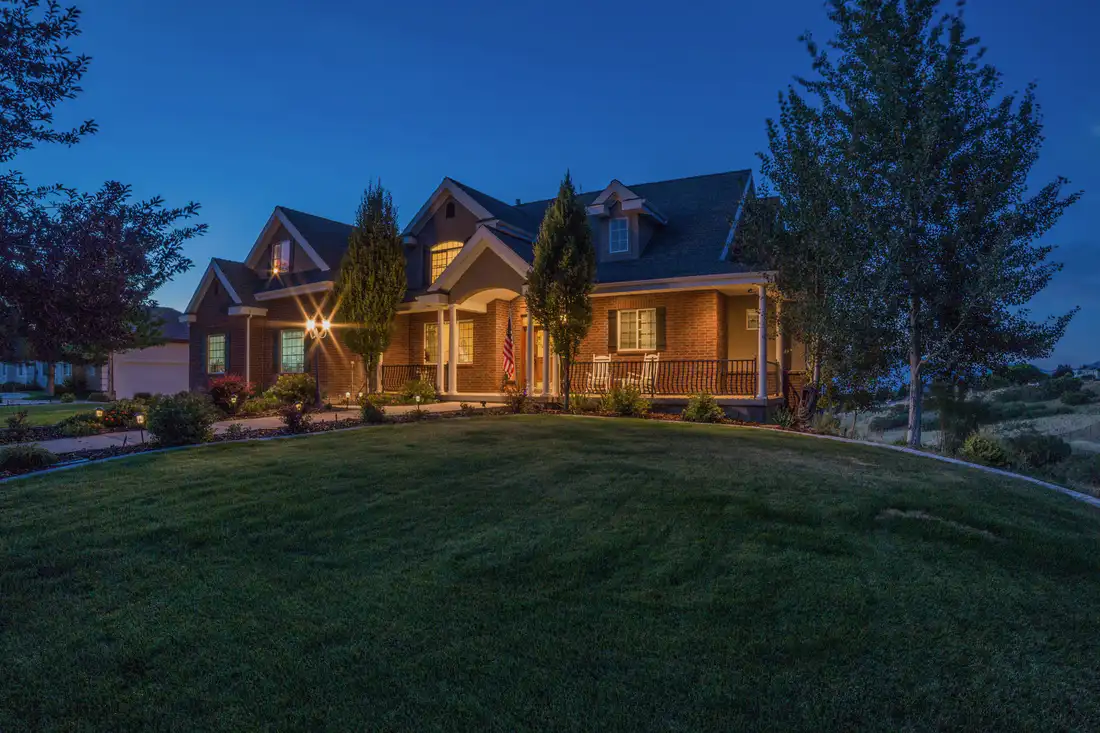 A house and lawn at twilight with the porch lit