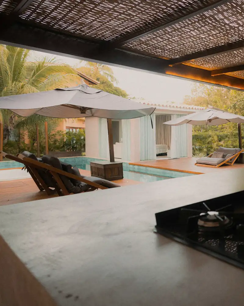 Outdoor kitchen counter with a cooktop under a slatted roof