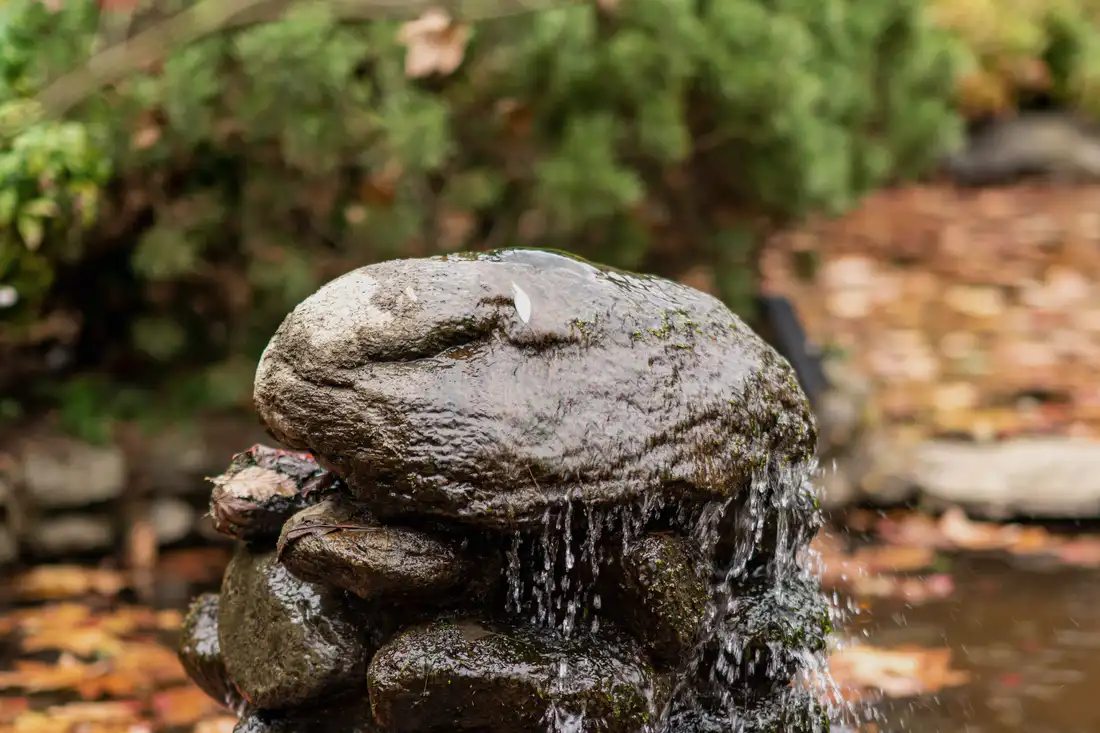 Water falling over a stone fountain into a planted basin