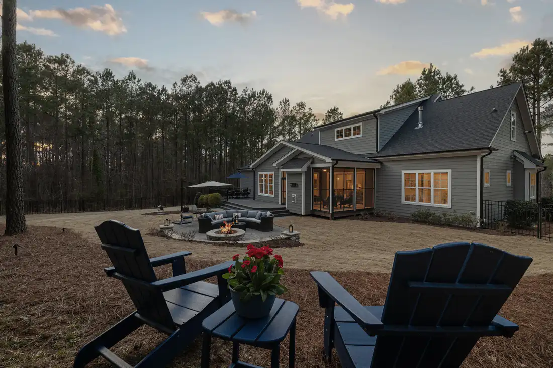 Fire pit and chairs on a gravel terrace behind a house at sunset