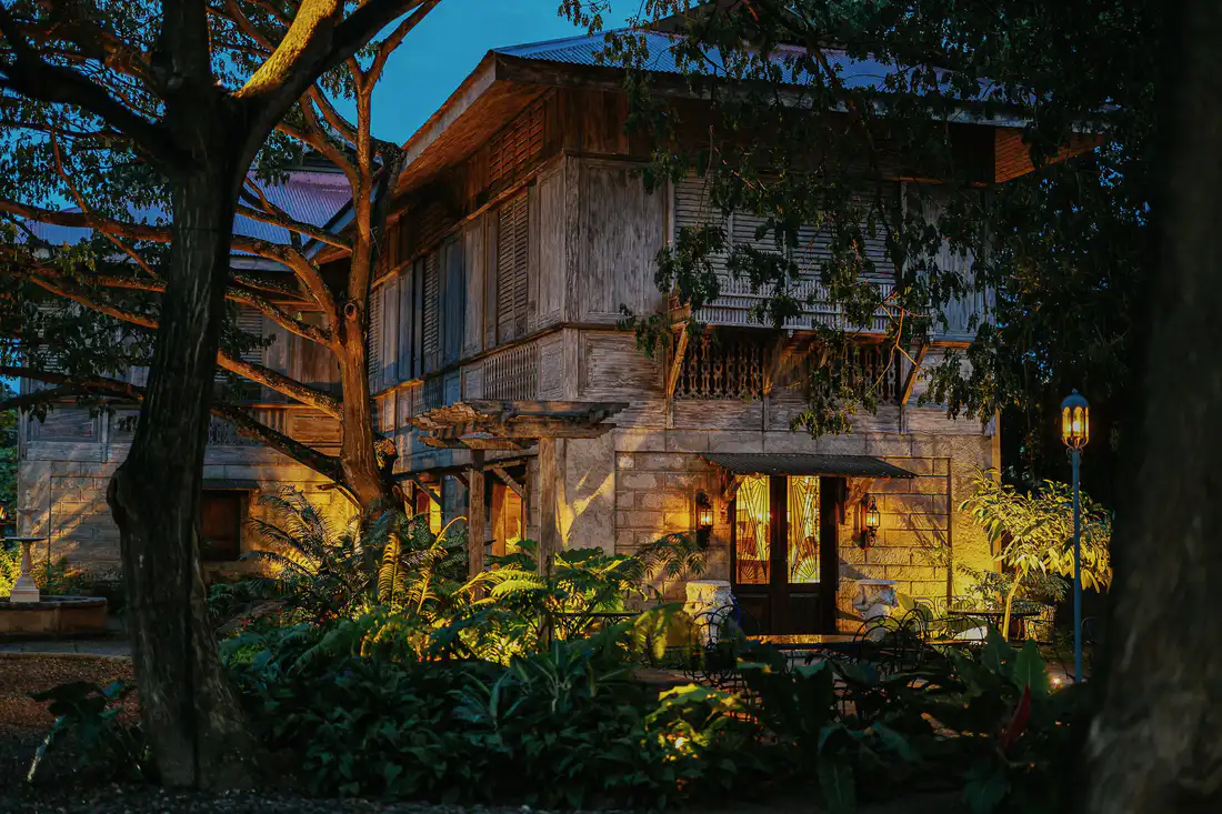 Mature trees uplit around a house at blue hour